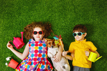 Little girl and boy, and his dog lying on green grass.の写真素材