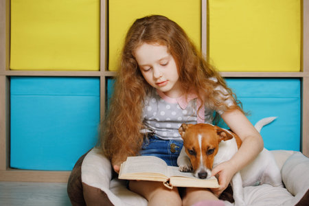 Girl and her friend dog jack russell reading the book.
