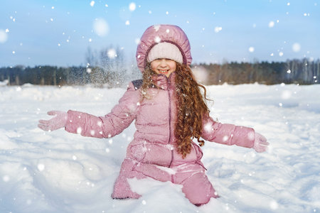 Little girl playing with snow. Falling snow around the child.の写真素材