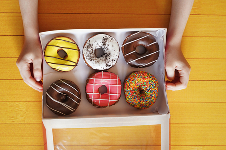 Child hand holding box with sweet donut dessert. Diet concept.の写真素材