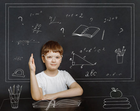Smart boy in a glasses with a book, pencil, pen and apple on the table. Back to school, easy...