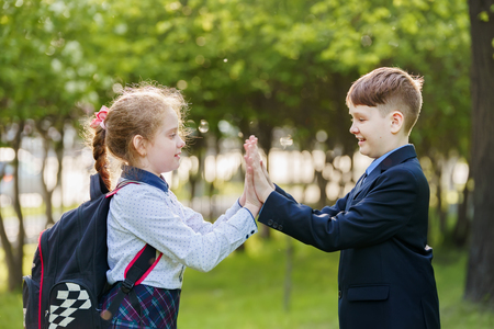 child friend enjoying clapping hands, or playing patty cake, or giving high five having fun together in spring park.の写真素材