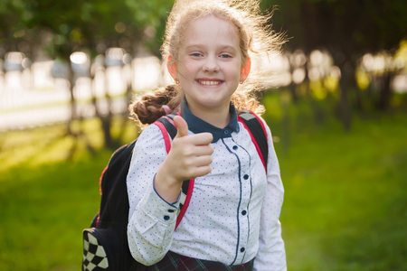 Happy school girl with white healthy  teeth showing a thumbs up gesture. Healthy, school, success, approval concept.の写真素材