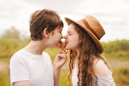 Children eat ice cream outdoors. Brothers and sister laugh and eat ice cream in the village in summer.の写真素材