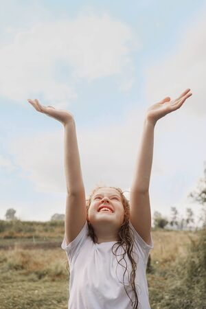 Laughing child spread its arms and catches raindrops and sunrayses. Freedom, happy childhood, healthy lifestyle concept.の写真素材