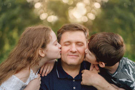 Cute children embracing and kissing his father. Little boy and girl kissing his dad on cheek.の写真素材