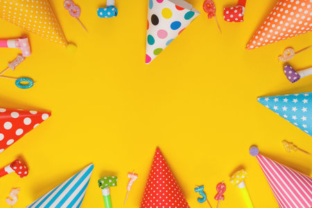 Colored party hat and candles lying on yellow background. Birthday, holiday concept.の写真素材