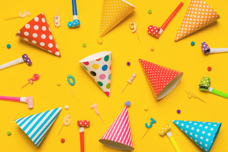 Party hat, candles, confetty, party blowers on yellow background with high top view. Celebration, child birthday concept.の写真素材
