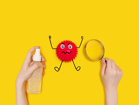 Child holding antiseptik spray and see the Covid-19 bacteria on table through a magnifying glass. Healthy, medical concept.の写真素材