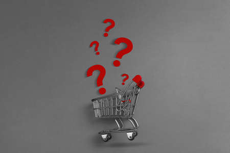 Shopping cart trolley and question mark on gray background top view copy space. Concept of shopping.の写真素材