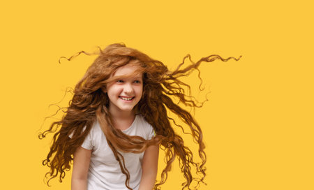 Portrait of teen girl with airy hair in white t-shirt wear on vivid yellow background.の写真素材