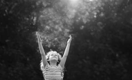 Cute little girl stretches her hand to catch sun rays. Religion, donation, people, charity, happy childhood, peace world concept.の写真素材