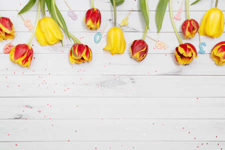 Yellow and red tulips on wooden table. Easter holiday background.の写真素材