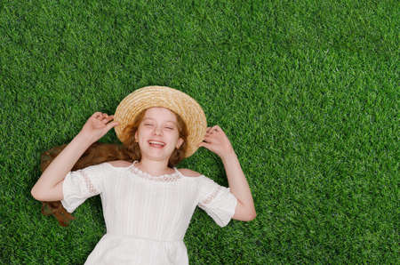 Happy spring day with high top view portrait the cute laughing girl resting on the green grass.の写真素材