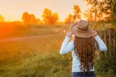 Curly girl in a straw hat resting in the summer sunset outdoor. vacation concept.