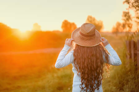 Curly girl in a straw hat resting in the summer sunset outdoor. vacation concept.の写真素材