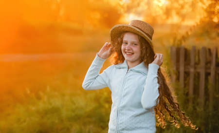Curly girl in a straw hat resting in the summer sunset outdoor. vacation concept.の写真素材