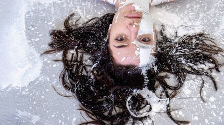 Portrait of a young woman with dark brown hair, in white color painted decorative. Creative expressive abstract body painting art, copy space.の写真素材