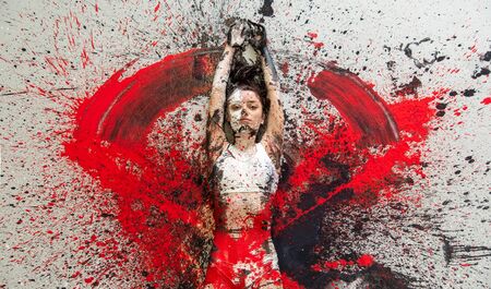 Young woman in underwear and sports bra lying on the floor elegantly decorative, in red, black and white color. Creative, expressive, abstract body art and painting.の写真素材