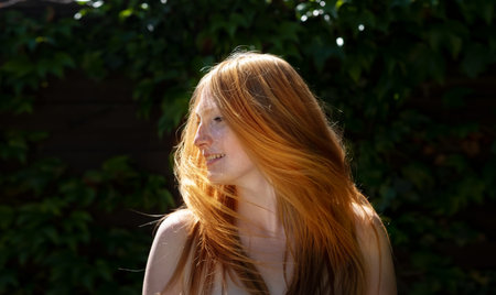 Sensual sexy portrait of young beautiful redhead woman shakes her red hair outdoors in the sunlight...