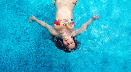 Top view to young sexy brunette woman in a colorful flower bikini , swimming in the turquoise spa pool, copy spaceの写真素材