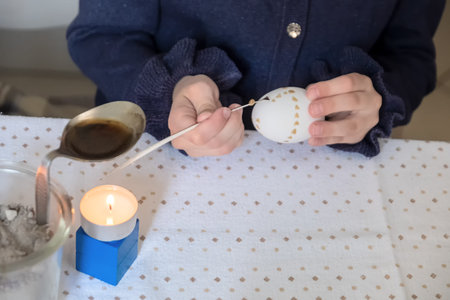 Child hand paints an Easter egg after Sorbian tradition with cut goose feather and candle wax.