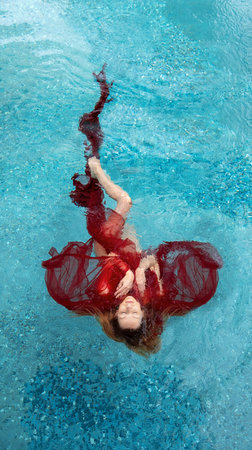 Top view of a beautiful young sexy woman in red dress, evening dress, towel floats weightlessly...