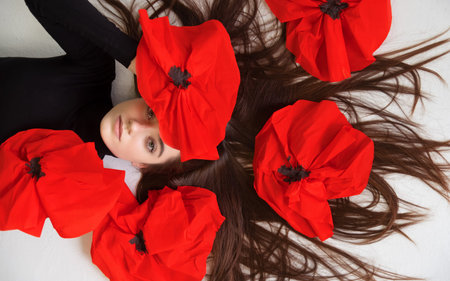 Portrait of beautiful young sexy woman lying on the white background floor with long wide hair and...
