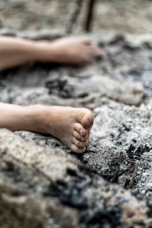 legs and feet of a sexy young dead woman lying in a burnt down fireplace between the gray ashes, copy spaceの写真素材