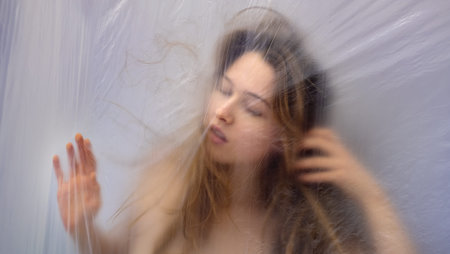 unique exotic extravagant portrait of beautiful sexy sensual seductive woman behind transparent plastic foil like in a dream as background, copy spaceの写真素材