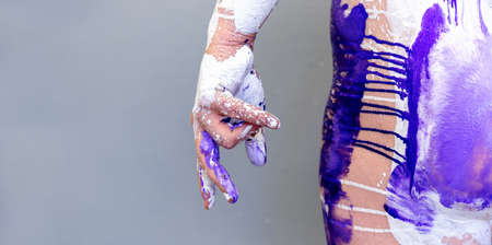 beautiful hand and hip of a young artistically abstract painted woman with white, pink and purple paint, creative body art painting, copy spaceの写真素材