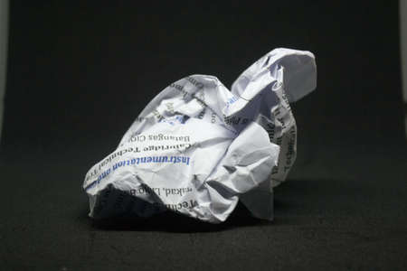 close up image of a crumpled piece of white paper with writings on a black backgroundの写真素材