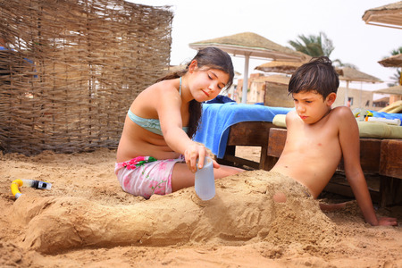 preteen siblings brother and sister have fun on sand beach play with sandの写真素材