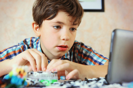preteen handsome boy have an online lesson how to make rainboy loom handmade toys