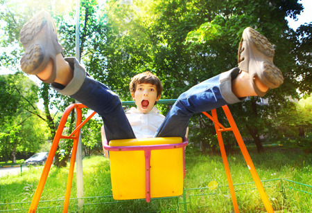 preteen handsome boy swinging on the swing in summer sunny dayの写真素材