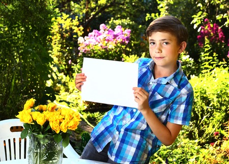 preteen handsome boy with paper sheet on the  summer garden backgroundの写真素材