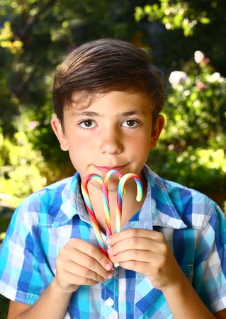 preteen handsome boy with rainbow candy sticks close up summer portraitの写真素材