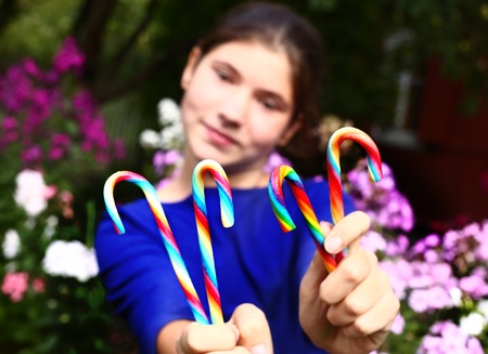 teen  girl with rainbow candy sticks close up portraitの写真素材