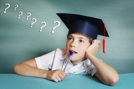 preteen handsome boy in graduation cap think about school subjectの写真素材