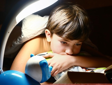 preteen  handsome boy read book with lamp before sleepの写真素材