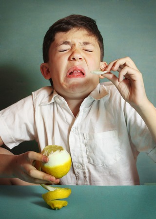 preteen  boy bite sore lemon make grimaceの写真素材