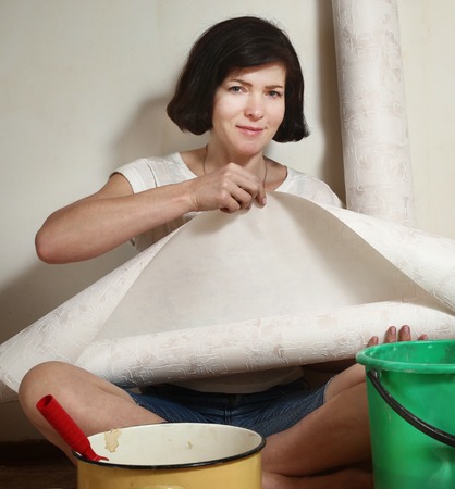 happy woman prepare to make a repair stick wallpapers with rollercoaster and clueの写真素材