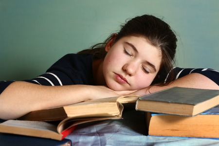 tired teenage girl sleep among book prepare for the last graduation school exam try to do her bestの写真素材