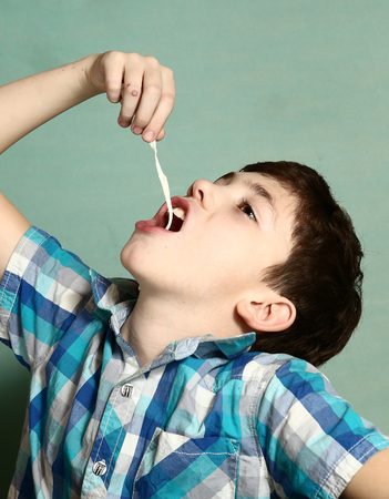 preteen boy pull chewing gum with his hand from mothの写真素材
