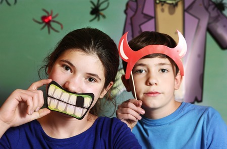 preteen boy and teenage girl brother and sister prepare for halloween party with spooky requisites and spider and frankenstein on the backgroundの写真素材