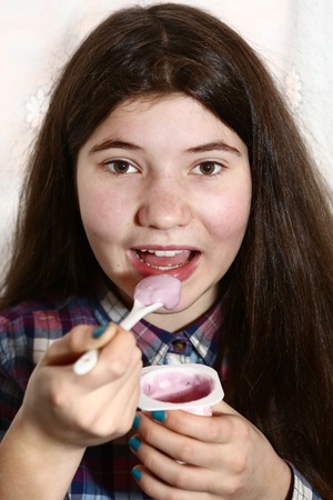 teenage pretty girl eat yogurt close up portrait isolated on whiteの写真素材