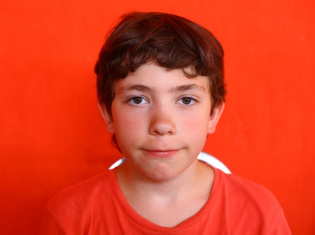 preteen handsome boy close-up portrait in red t-shirt on red wall backgroundの写真素材