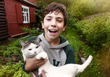 preteen handsome boy with siberian tom cat close up country summer portrait with cottage house on the backgroundの写真素材