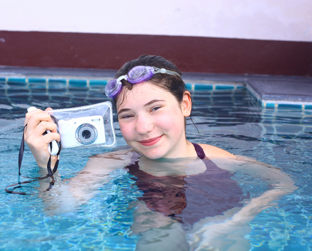 teenage pretty girl in water glasses close up portrait with camera in underwater protection slip in open air swimming poolの写真素材