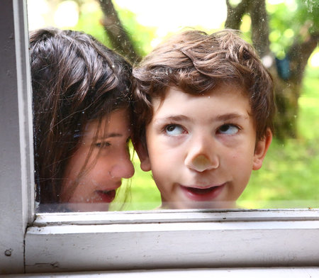 teen siblings couple brother and sister close up photo through the window on the summer garden...